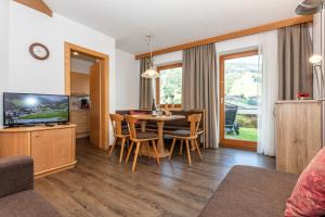 salon ze stołem, krzesłami i telewizorem w obiekcie Apartment Hintermaisalm w Saalbach Hinterglemm