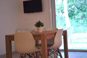 mesa de comedor con sillas blancas y TV en Appartement charmant en Corse avec terrasse au calme, en Santa-Lucia-di-Moriani
