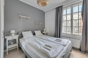 Un dormitorio blanco con una cama grande y una ventana en Comfort Apartments Długi Targ, en Gdansk