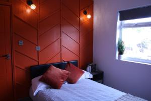 1 dormitorio con cabecero de madera y 1 cama con almohadas rojas en Perfect Private Room Accommodation with own kitchenette in Peterborough, en Peterborough