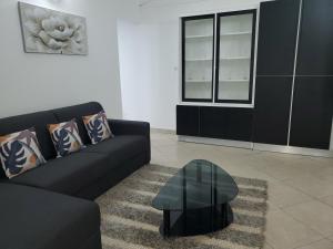 uma sala de estar com um sofá preto e uma mesa em L'Aurielle, Tout le confort à 500m de la plage em Sainte-Rose