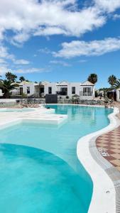 una piscina de agua azul y edificios blancos en Casa Ayla Montecastillo A8, en Caleta de Fuste