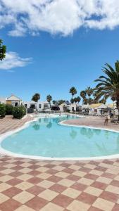 a large swimming pool in a resort with a checkered floor at Casa Ayla Montecastillo A8 in Caleta De Fuste