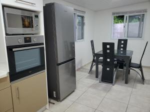 uma cozinha com uma mesa e um frigorífico de aço inoxidável em L'Aurielle, Tout le confort à 500m de la plage em Sainte-Rose