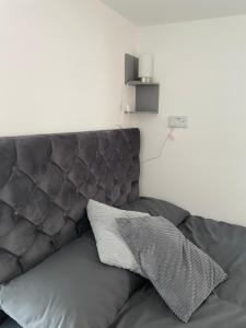 a gray couch with a pillow on top of it at Private en-suite garden room in Countess Wear +16 photos