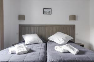two beds sitting next to each other with towels on them at Hotel Les Palmiers En Camargue in Saintes-Maries-de-la-Mer
