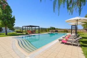 a swimming pool with chairs and an umbrella at Villa Amarandes by Villa Plus in Paradeísion