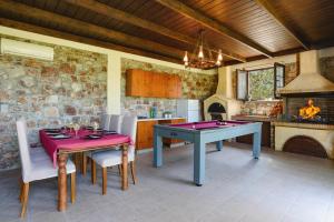 uma sala de jantar com uma mesa de pingue-pongue e uma lareira em Villa Amarandes by Villa Plus em Paradeísion