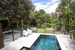 a swimming pool with two chairs and a fence at Casuarina Beachfront House - Hostie Properties in Casuarina