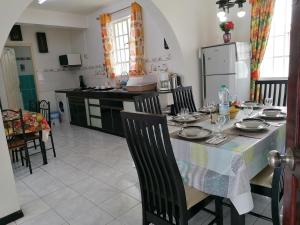 een keuken met een tafel met stoelen en een tafelkleed erop bij Les Camelias Ground Floor in Flic-en-Flac