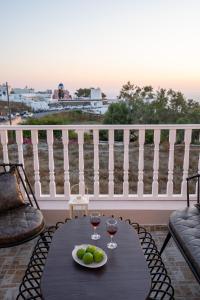 a table with two glasses of wine on a balcony at Amarie House with Sea View & Sunset View in Oia