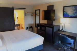 a hotel room with a bed and a desk and a television at Travelodge by Wyndham Santa Rosa Wine Country in Santa Rosa