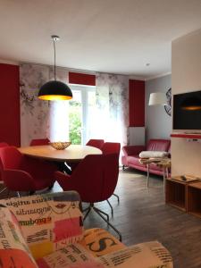 a living room with a table and red chairs at Große Prinzessin - Appartement mit Saunanutzung in Burgbernheim