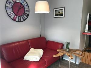 - un canapé rouge dans une chambre avec une horloge murale dans l'établissement Große Prinzessin - Appartement mit Saunanutzung, à Burgbernheim