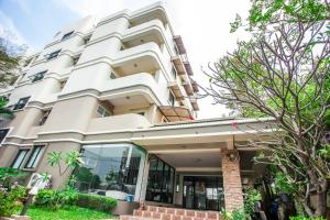 a large white building with trees in front of it at Baan Boonanan Apartment in Ban Talat Rangsit