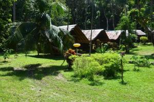 a garden with a palm tree and a house at Paradise Lost Bungalows in Koh Kradan