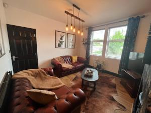 a living room with a leather couch and a table at Modern mid terrace villa, Royston, Barnsley in Royston