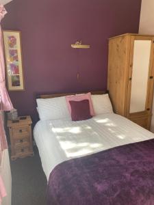 a bedroom with a large bed with purple walls at White Heather Guest House in Mablethorpe