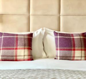 two pillows are sitting on a bed next to a headboard at Mallyan Spout Hotel in Goathland