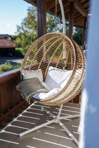 a wicker chair sitting on a porch with pillows at Ferienwohnung "Wie dahoam" in Chieming