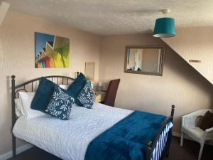 a bedroom with a bed with blue pillows at White Heather Guest House in Mablethorpe