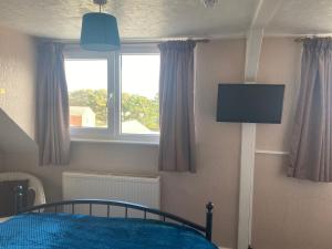 a bedroom with a bed and a window and a tv at White Heather Guest House in Mablethorpe