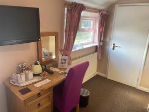 a room with a desk with a purple chair and a mirror at White Heather Guest House in Mablethorpe