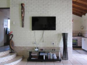 a living room with a tv on a white brick wall at Manzini Chalet No 34 in St Lucia
