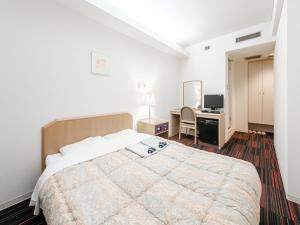 um quarto com uma cama e uma secretária com um computador em Hotel Tetora Spirit Sapporo em Sapporo