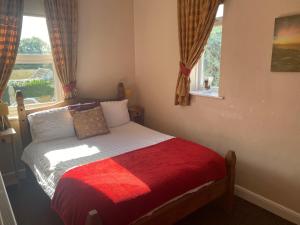 a bedroom with a bed with a red blanket and a window at White Heather Guest House in Mablethorpe