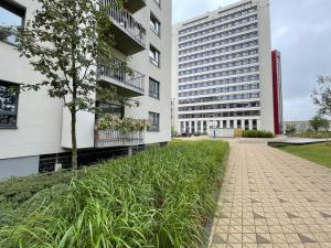 a building with a grass field next to a building at Jauna Teika Cosy 1bdr apartment, self check-in in Rīga