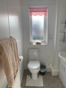 a white bathroom with a toilet and a window at White Heather Guest House in Mablethorpe