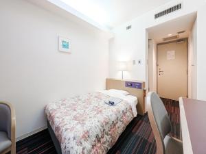 札幌市にあるHotel Tetora Spirit Sapporoのベッドと椅子付きの小さな部屋です。