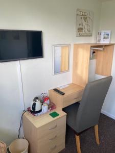 a room with a desk and a chair and a tv at White Heather Guest House in Mablethorpe