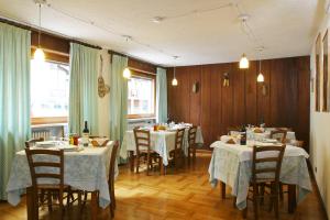 een eetkamer met tafels met witte tafelkleden bij Hotel Biancaneve in Sauze dʼOulx