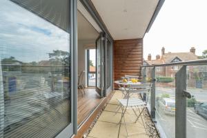 a room with a balcony with a table and chairs at 2 King Georges - Aldeburgh Coastal Cottages in Aldeburgh
