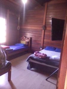 a room with two beds and a chair in a cabin at Hostel Park in Uberlândia