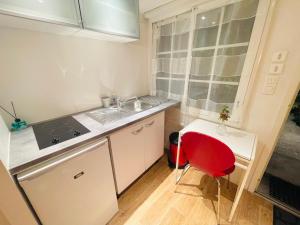 una pequeña cocina con fregadero y silla roja en La petite Maison dans la Croix Rousse, en Lyon