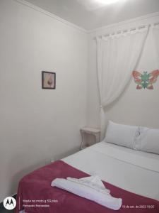 um quarto com uma cama branca e uma imagem de borboleta na parede em solar das margaridas em Paraty