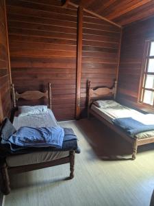 two beds in a room with wooden walls at Hostel Park in Uberlândia