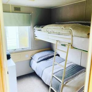 a bunk room with two bunk beds and a window at Birchlea Caravan in Stonehaven