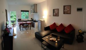sala de estar con sofá negro y cocina en Orchidilla Residence Phuket Mai Khao Beach - SHAPlus, en Mai Khao Beach