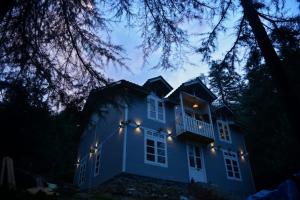 a blue house with lights on it at night at Woodzo Shangarh in Sainj