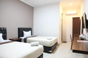 a hotel room with two beds and a desk at Rahayu Hotel Cirebon in Cirebon