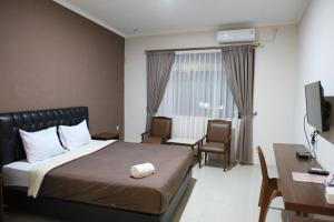 チルボンにあるRahayu Hotel Cirebonのベッド、デスク、テレビが備わるホテルルームです。