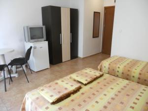 a hotel room with two beds and a tv at Стаи под наем "Таня"- безплатен паркинг in Ahtopol