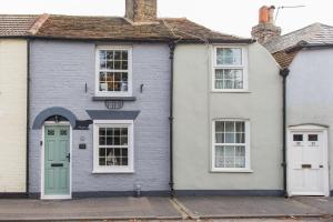 a white house with a green door and windows at Cow and Cockle - quirky cottage in the centre of Deal in Deal