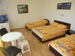 a room with three beds and a table and chairs at Вила "Таня" in Ahtopol