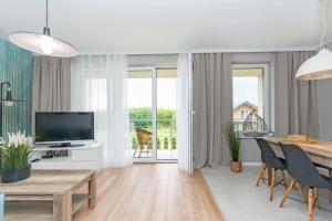 Una sala de estar con un televisor y una mesa y sillas. en Słoneczne Tarasy I, en Gdansk