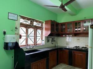 a kitchen with green walls and a ceiling fan at Luxurious 5BHK Peace Villa Siridao Goa Beach in Panaji